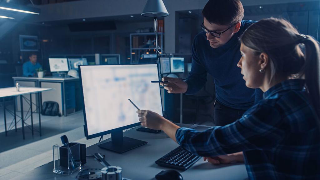 A man and a woman analyzing machine vision data on a computer monitor.