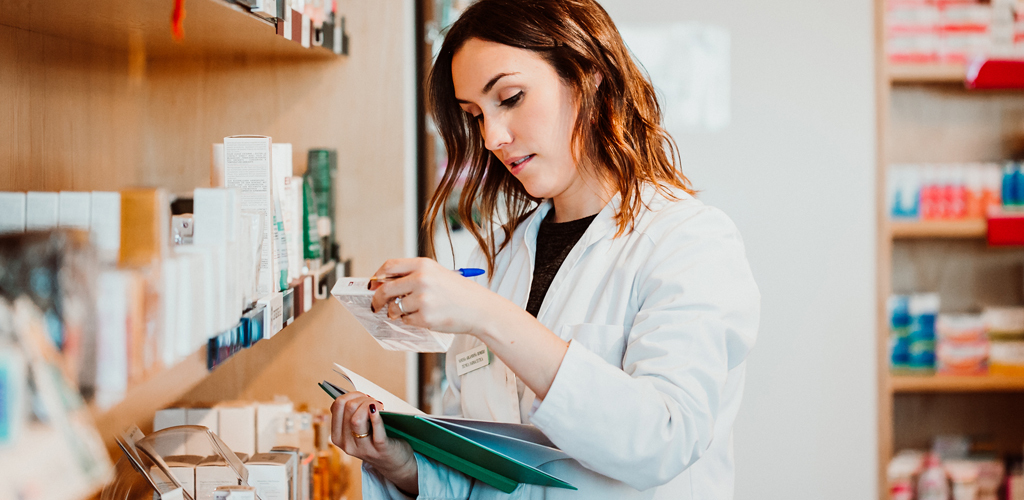 Female doctor reviewing medication against a folder of filings.